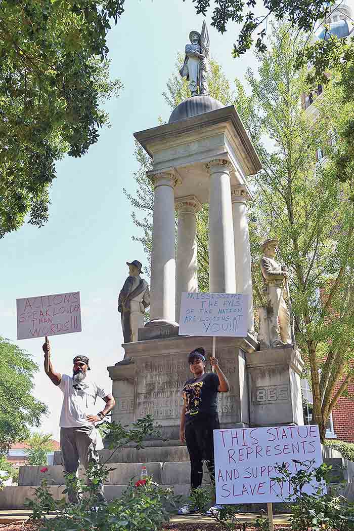 People hold signs calling for removal of Confederate monument in Columbus, Mississippi
